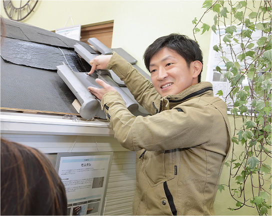 ショールームでお客様に屋根の素材についてご説明している様子